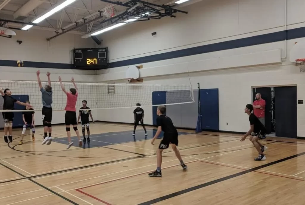 Players positioned to receive an incoming spike, demonstrating focus and readiness on the volleyball court.