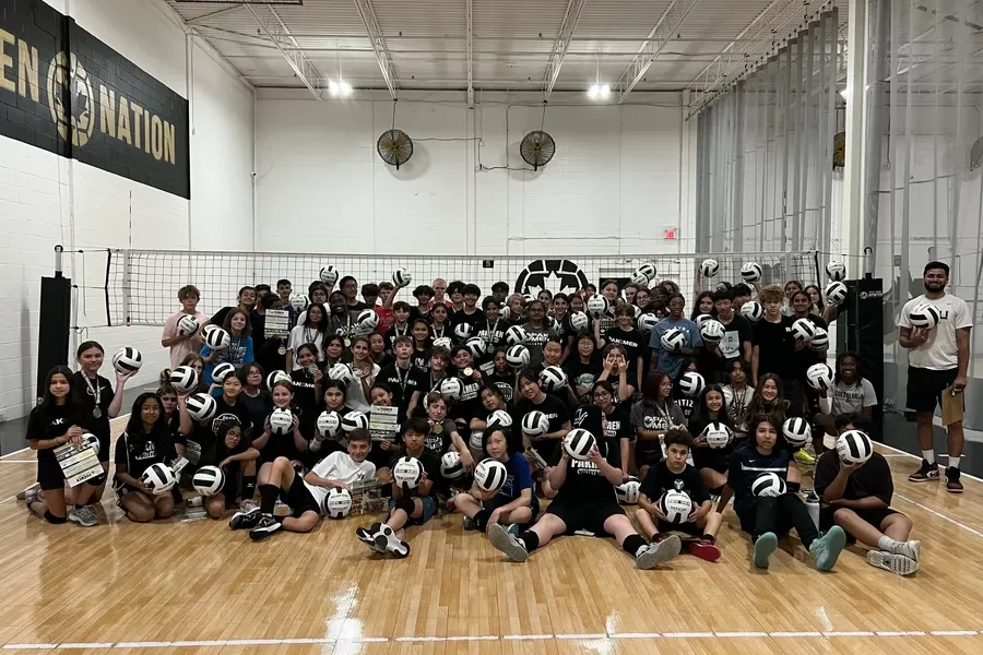 Group of volleyball players and coaches posing for a team photo, celebrating teamwork and camaraderie.